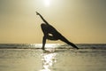 Silhouette of woman standing at yoga pose on the tropical beach during sunset. Girl practicing yoga near sea water Royalty Free Stock Photo