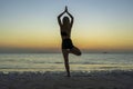 Silhouette of woman standing at yoga pose on the tropical beach during sunset. Girl practicing yoga near sea water Royalty Free Stock Photo
