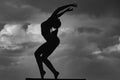 Silhouette of woman stretching. Young girl practicing yoga, doing fit exercise, working out. Dance studio. Cloudy sky Royalty Free Stock Photo