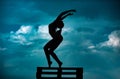 Silhouette of woman stretching. Young girl practicing yoga, doing fit exercise, working out. Dance studio. Cloudy sky Royalty Free Stock Photo