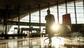 Silhouette of woman stucked at airport terminal over flight cancellation,calling family, sitting in almost empty airport