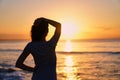 Silhouette of a woman at sunrise. The girl looks at the sea and the setting sun. Royalty Free Stock Photo
