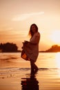 Silhouette of woman at sunset. Young happy woman is standing in sea in rays of the setting sun on summer evening Royalty Free Stock Photo