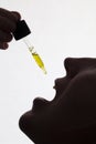 Silhouette of a woman taking drops of CDB oil