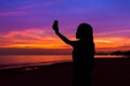 Silhouette of woman taking photo of sunset with mobile phone, at Royalty Free Stock Photo