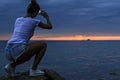 Silhouette of woman taking photo after sunset. Royalty Free Stock Photo