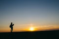 Silhouette of a woman taking pictures on the camera at sunset background Royalty Free Stock Photo