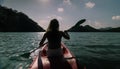 Silhouette of woman tourist raising hands while sailing in canoe along sea bay water to distant hilly island backside Royalty Free Stock Photo