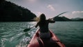 Silhouette of woman tourist raising hands while sailing in canoe along sea bay water to distant hilly island backside Royalty Free Stock Photo