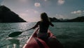 Silhouette of woman tourist raising hands while sailing in canoe along sea bay water to distant hilly island backside Royalty Free Stock Photo