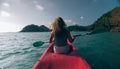 Silhouette of woman tourist raising hands while sailing in canoe along sea bay water to distant hilly island backside Royalty Free Stock Photo