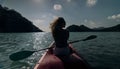Silhouette of woman tourist raising hands while sailing in canoe along sea bay water to distant hilly island backside Royalty Free Stock Photo