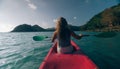 Silhouette of woman tourist raising hands while sailing in canoe along sea bay water to distant hilly island backside Royalty Free Stock Photo