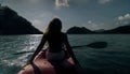 Silhouette of woman tourist raising hands while sailing in canoe along sea bay water to distant hilly island backside Royalty Free Stock Photo