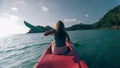 Silhouette of woman tourist raising hands while sailing in canoe along sea bay water to distant hilly island backside Royalty Free Stock Photo