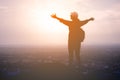 The silhouette of a woman tourist spread his arms wide as a winner or freedom on the landscape