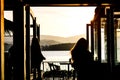 Silhouette of woman walking into cafe side the sea with beautiful blazing sunset landscape at mountain, sea and orange sky Royalty Free Stock Photo