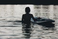 silhouette of woman in water with paddle board