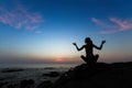 Silhouette of woman yoga in Lotus position on the shore of ocean at evening Royalty Free Stock Photo