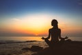 Silhouette of woman yoga in Lotus position on the shore of ocean. Royalty Free Stock Photo