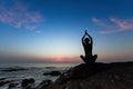 Silhouette of woman yoga position on the shore of ocean at meditation evening Royalty Free Stock Photo