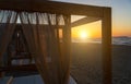 Silhouette wooden with blinds gazebo on an empty sandy beach on a sunset background. Royalty Free Stock Photo