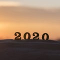 Silhouette of 2020 wooden numbers on the sand on the beach at sunset. Setting sun. The symbol of the outgoing year. 2021.