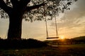 Silhouette of a wooden swing under the tree. Lonely and relaxing golden light on sunset on summer Royalty Free Stock Photo