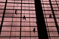 A silhouette of a worker cleaning windows hangs from a rope in the airport building
