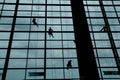 A silhouette of a worker cleaning windows hangs from a rope in the airport building