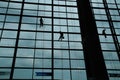 A silhouette of a worker cleaning windows hangs from a rope in the airport building