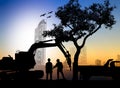 silhouette worker with Loaders and trucks in a building site over Blurred city