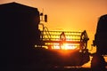 Silhouette of working combine against sun, sunset over the field