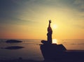 Silhouette yoga girl by the beach at sunrise doing meditation