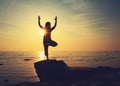 Silhouette yoga girl by the beach at sunrise doing standing pose Royalty Free Stock Photo