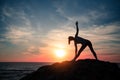 Silhouette of yoga woman doing exercises on the sea beach during sunset Royalty Free Stock Photo