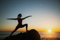 Silhouette yoga woman doing fitness exercises near the sea at sunset. Sport. Royalty Free Stock Photo