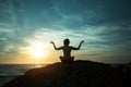 Silhouette of Yoga woman sitting in Lotus position on the ocean beach during sunset. Royalty Free Stock Photo