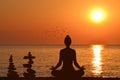 Silhouette of yogi in lotus position and a piles of stones at sea shore Royalty Free Stock Photo