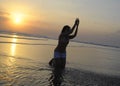 Silhouette of young Asian woman playing with sand and water on sea at sunset beach happy and excited Royalty Free Stock Photo