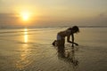 Silhouette of young Asian woman playing with sand and water on sea at sunset beach happy and excited Royalty Free Stock Photo