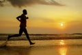 Silhouette of young athletic and fit african american sport man doing running workout on sunset at the beach training hard jogging Royalty Free Stock Photo