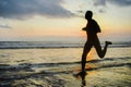 Silhouette of young athletic and fit african american sport man doing running workout on sunset at the beach training hard jogging Royalty Free Stock Photo