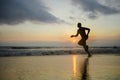 Silhouette of young athletic and fit african american sport man doing running workout on sunset at the beach training hard jogging Royalty Free Stock Photo