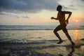 Silhouette of young athletic and fit african american sport man doing running workout on sunset at the beach training hard jogging Royalty Free Stock Photo