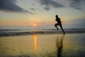 Silhouette of young attractive fit athletic and strong black afro American man running at sunset beach training hard and sprinting