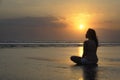 Silhouette of young beautiful asian woman sitting on sand water free and relaxed looking at the sun on sunset beach