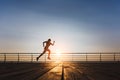 Silhouette of a young beautiful athletic girl with long blond hair in black clothes running at sunrise over the sea Royalty Free Stock Photo