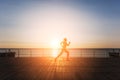 Silhouette of a young beautiful athletic girl with long blond hair in black clothes running at sunrise over the sea Royalty Free Stock Photo