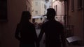 Silhouette of young beautiful couple in love walking around the old city center